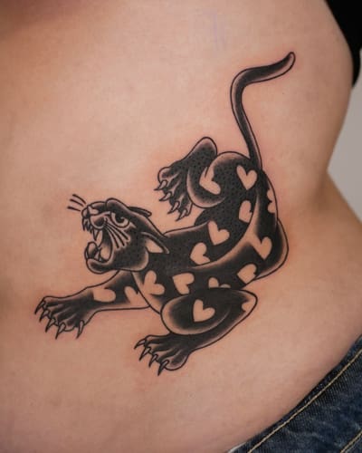 Panthère noire aux taches en forme de cœur tatouée sur le flanc